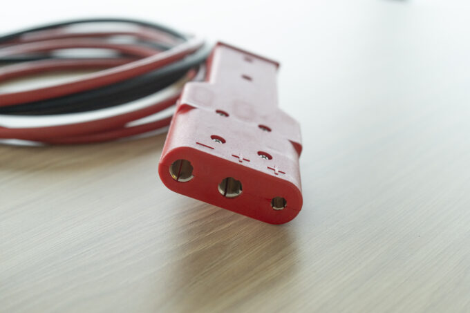 Photo of a 3-pin connector of a GPU cable, especially for use with the TowFLEXX TF1 and TF2 aircraft tugs. The plug is clearly visible and in focus, with clearly recognizable connections and a robust design that ensures a reliable and secure connection